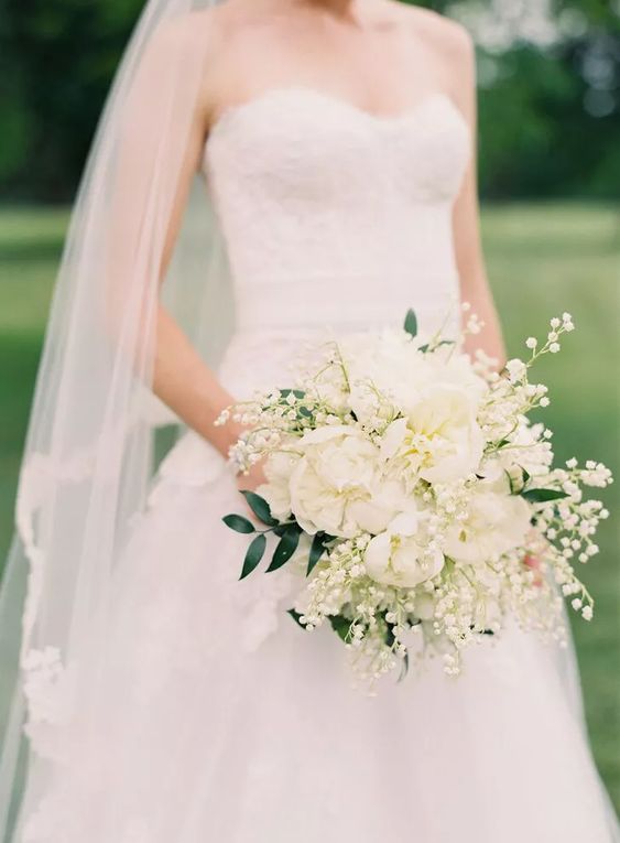 a white wedding bouquet of white peonies, lily of the valley and greenery is a lovely idea for a spring or summer bride