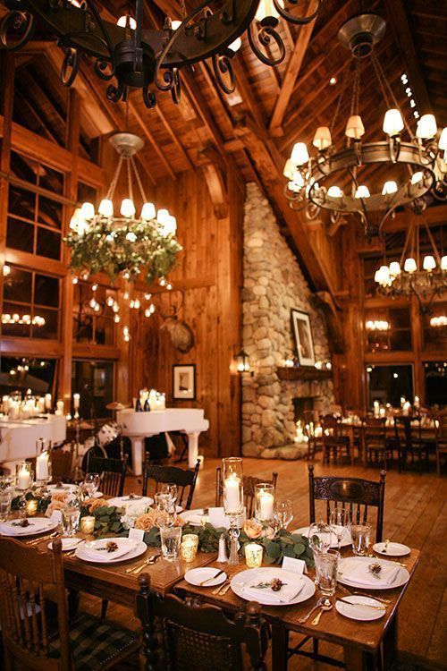 a beautiful chalet wedding reception space with chandeliers and greenery, with greenery and blush rose runners, white porcelain and pinecones