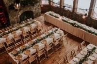 18 a beautiful chalet wedding reception with a stone fireplace, textural greenery runners, gold chargers and lights over the space
