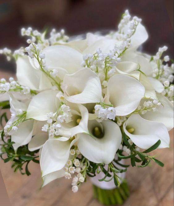 an all-white wedding bouquet of calla lilies and lily of the valley is a very exotic combo for a refined spring or summer wedding