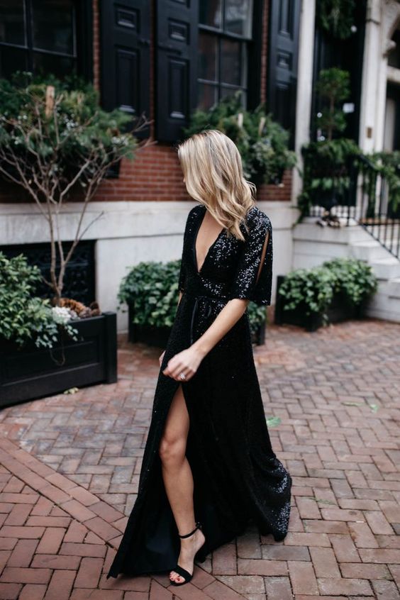 a black sequin maxi dress with a slit and a deep neckline, short sleeves with slits, black block heels to shine bright