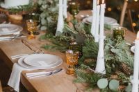 22 a gorgeous chalet wedding table setting with an evergreen and pinecone table runner, tall candles, white porcelain and amber glasses