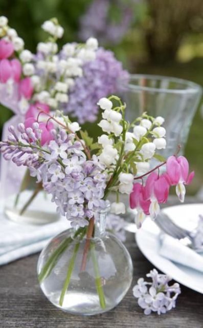 a beautiful and relaxed wedding centerpiece of a clear vase with lilac, white and pink blooms is a lovely idea for a spring wedding