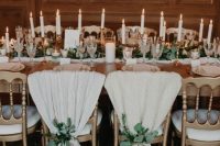 28 a refined chalet wedding tablescape with a white and greenery runner, candles in gilded candelholders, pillar candles and blankets on the chairs