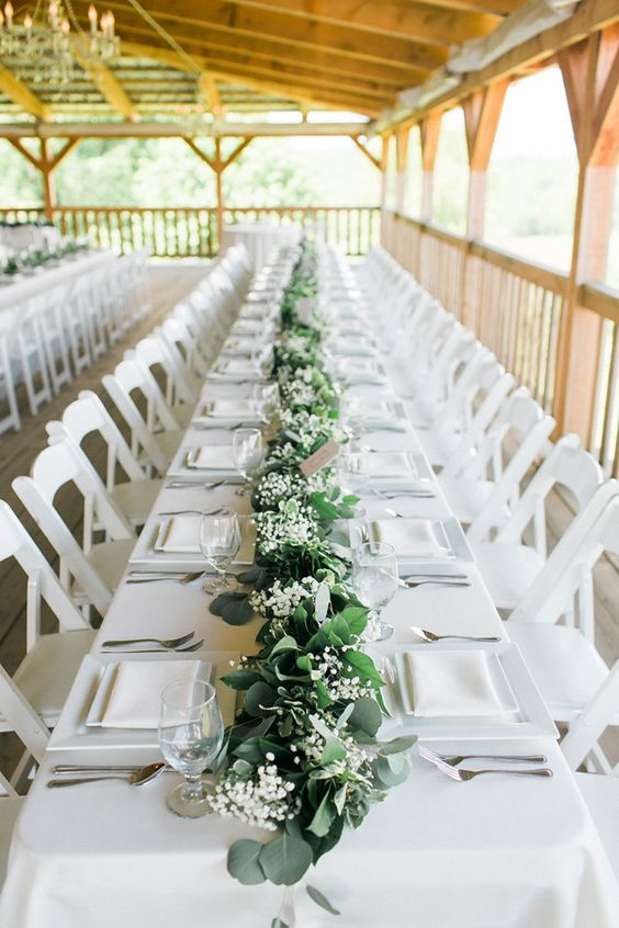 a gorgeous wedding tablescape done in white, with a greenery and lily of the valley table runner that refreshes the table