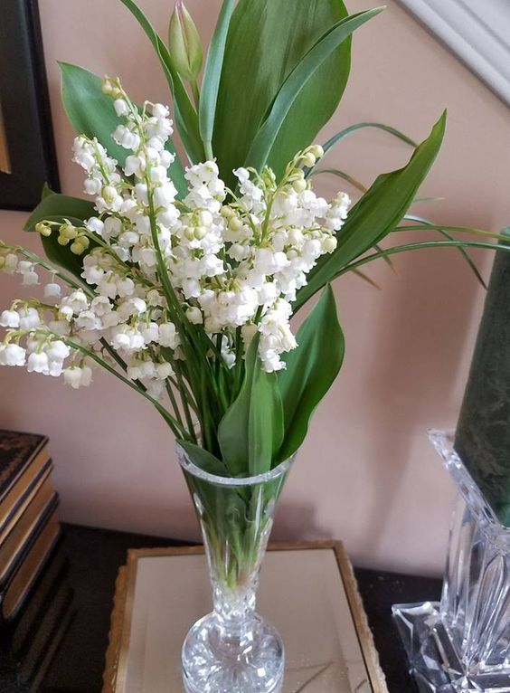 a vintage glass with foliage and lily of the vally is a lovely idea for a spring wedding and you can DIY such a centerpiece easily