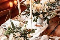 32 a sophisticated chalet wedding tablescape with neutral linens, lush white florals, tall and thin candles and greenery and gold cutlery