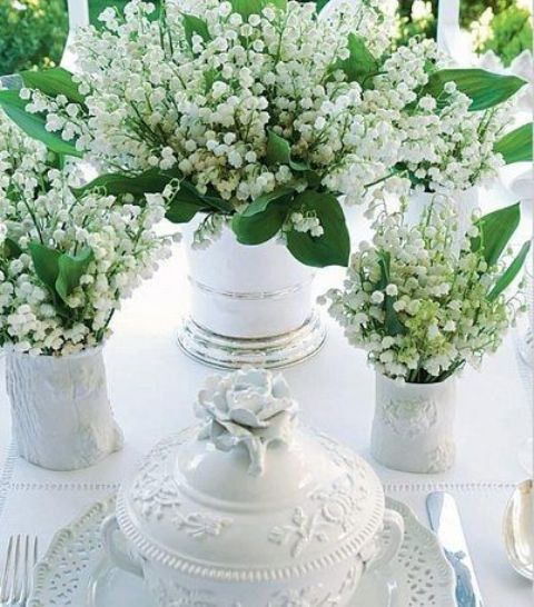 a vintage wedding tablescape in white, with vintage vases and lily of the valley, with chic porcelain and neutral linens