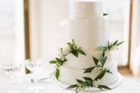 34 a white buttercream wedding cake decorated with lily of the valley and greenery is a very chic and beautiful idea for spring