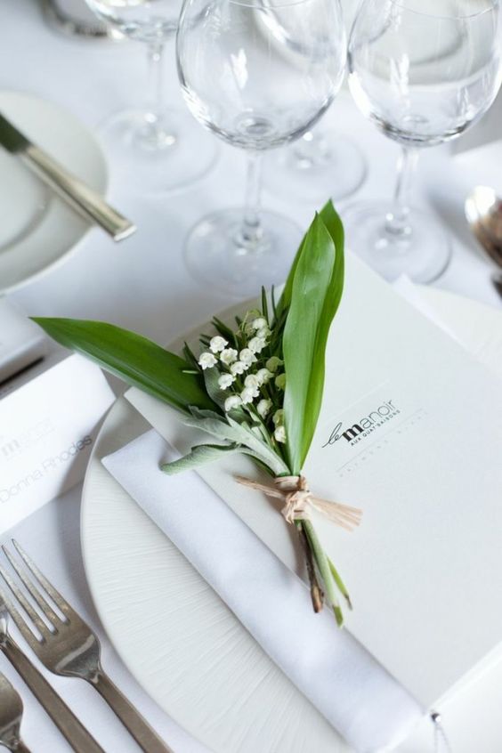 a white wedding tablescape with elegant porcelain and cutlery, with a lily of the valley card and a menu is very chic