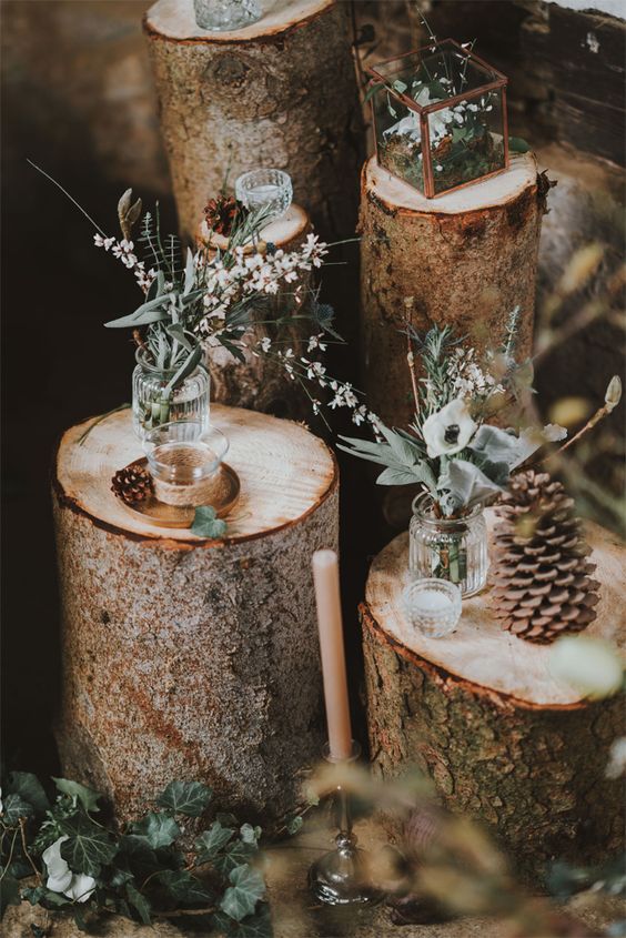 lovely winter lodge wedding decor of tree stumps, pinecones, greenery and cotton branches and boxes with moss and blooms