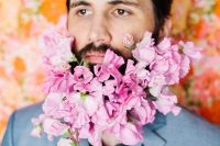 a beard with lots of pink blooms that add a bit of romance to the groom’s look and make him look like a flower child