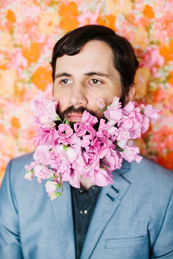 a beard with lots of pink blooms that add a bit of romance to the groom's look and make him look like a flower child