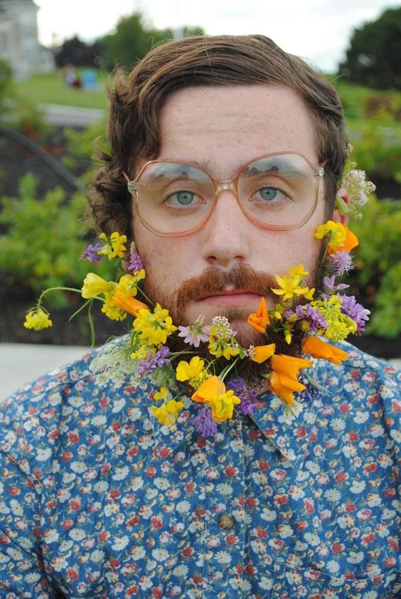a hipster summer groom wearing a blue floral shirt and a beard accented with yellow, orange and purple blooms with plenty of dimension