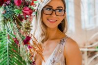 a romantic bridal look with an A-line celestial wedding dress with a deep neckline, thick straps and statement black framed eyeglasses