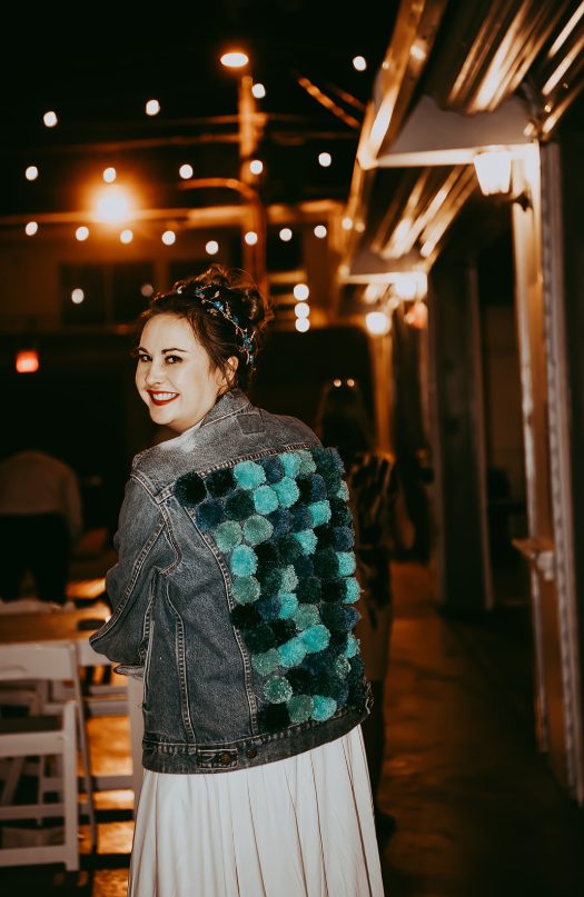 a bride wearing a blue denim jacket and accented with turquoise, dark green and navy pompoms for a unique touch