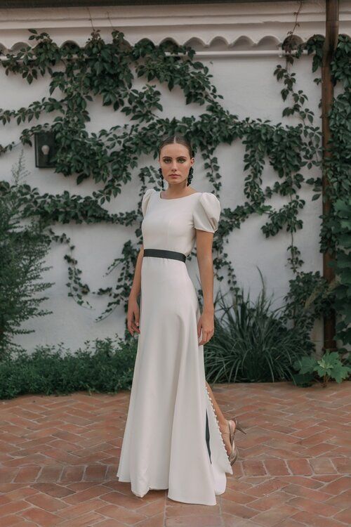 a modern plain A-line wedding dress with a high neckline, puff short sleeves, a back slit with buttons, a black sash and black earrings for a chic look
