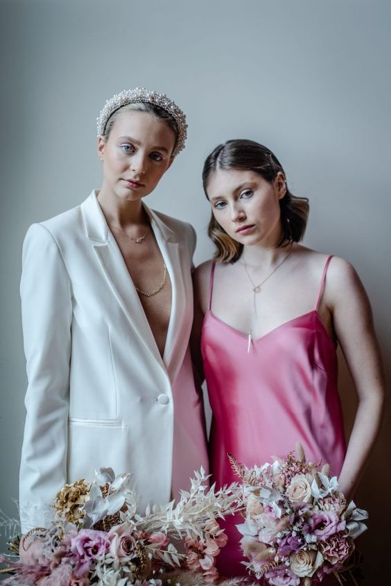 one bride wearing a white pantsuit, the other bride rocking a hot pink slip wedding dress are a fantastic and out of the box idea for a modern wedding