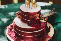 04 a boho fall red velvet wedding cake with glazing, with bold burgundy blooms, berries and wheat, with gold deer cake toppers is super cool