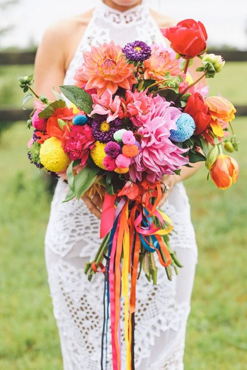 a colorful wedding bouquet of orange, red, purple blooms and colorful pompoms of various sizes plus bright ribbons is amazing
