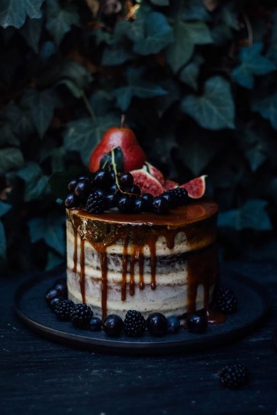 a decadent semi naked wedding cake with caramel drip, berries, pears and figs on top for fall