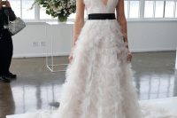 05 a romantic lace A-line wedding dress with a plunging neckline, no sleeves, a black sash for an accent and black earrings by Marchesa