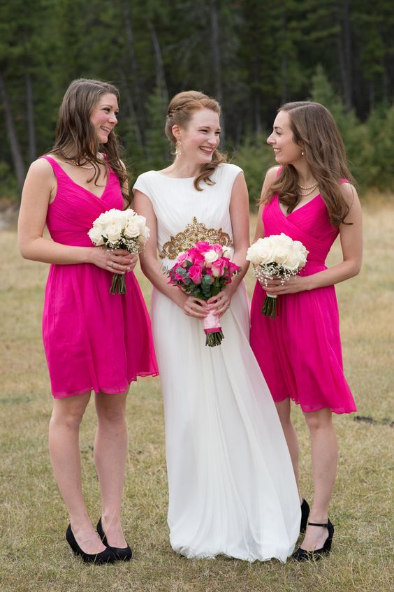 bridesmaids wearing hot pink knee bridesmaid dresses with draped bodices and thick straps plus black shoes look nice and bold
