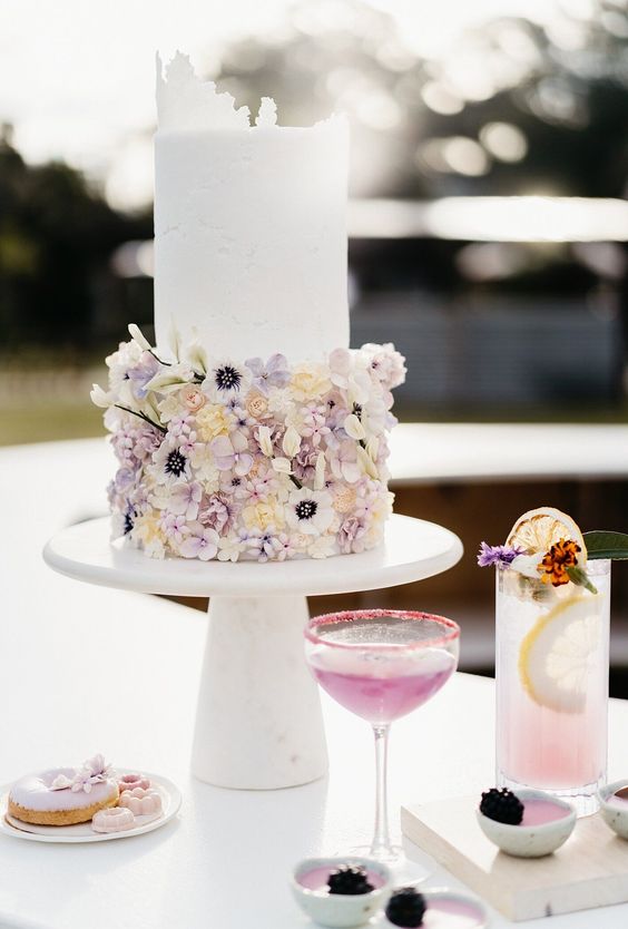 a delicate and refined wedding cake with a white and pink and lilac floral tier, with a raw edge is a gorgeous idea for a pastel spring wedding