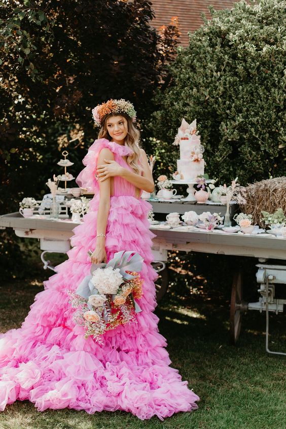 a whimsical hot pink A-line tulle wedding dress with a plunging neckline and a tiered skirt with a long train - such dresses are among the hottest current trends