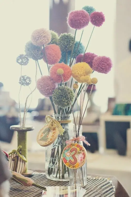 a bright fiesta wedding centerpiece with colorful pompoms on sticks, with colorful embroidery hoops and numbers is amazing