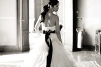 12 a beautiful strapless A-line wedding dress with a layered skirt with a train, an open back and a black sash with a bow on the back for an elegant touch