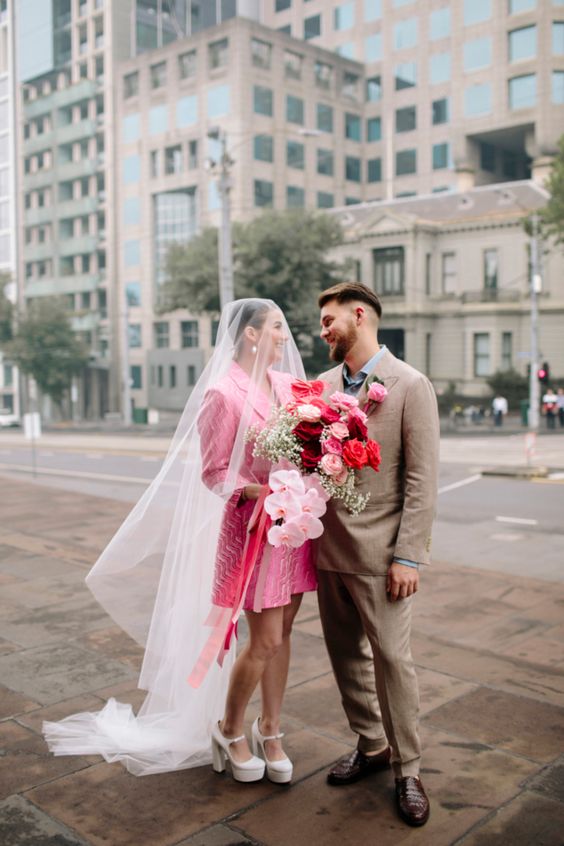 a printed hot pink blazer wedding dress, a veil and white platform shoes for a fashion-forward bridal look