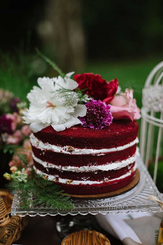 a stylish and cool red velvet wedding cake with pink, fuchsia, red and white blooms on top is a lovely idea for a boho woodland wedding