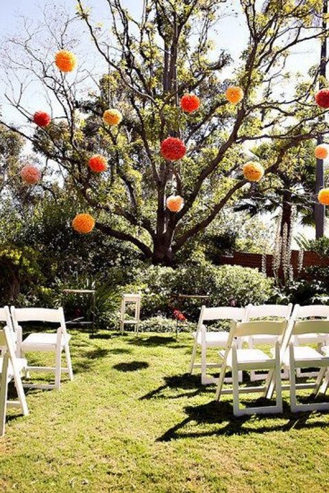 a living tree decorated with oversized colorful pompoms instead of blooms is a fresh eco-friendly idea that really works and won't cost a pretty penny