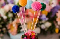 15 a naked wedding cake with berries and blooms, with colorful pompoms on sticks is a lovely idea for a cheerful party wedding