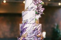 16 a jaw-dropping wedding cake with purple and black patterns painted on it, with gold foil and gorgeous purple blooms on top