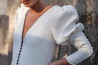 16 a modern plain white wedding dress with a plunging neckline, puff sleeves, black buttons on the front and sleeves, gold statement earrings