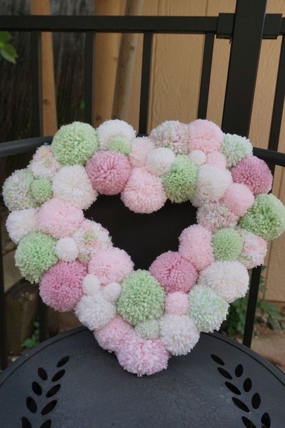 a pastel pompom heart wreath is a beautiful and easy DIY decor idea for any wedding, especially for a spring one