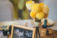 17 a pretty and simple wedding centerpiece of yellow pompoms, a wood slice, some candles and a chalkboard sign is wow