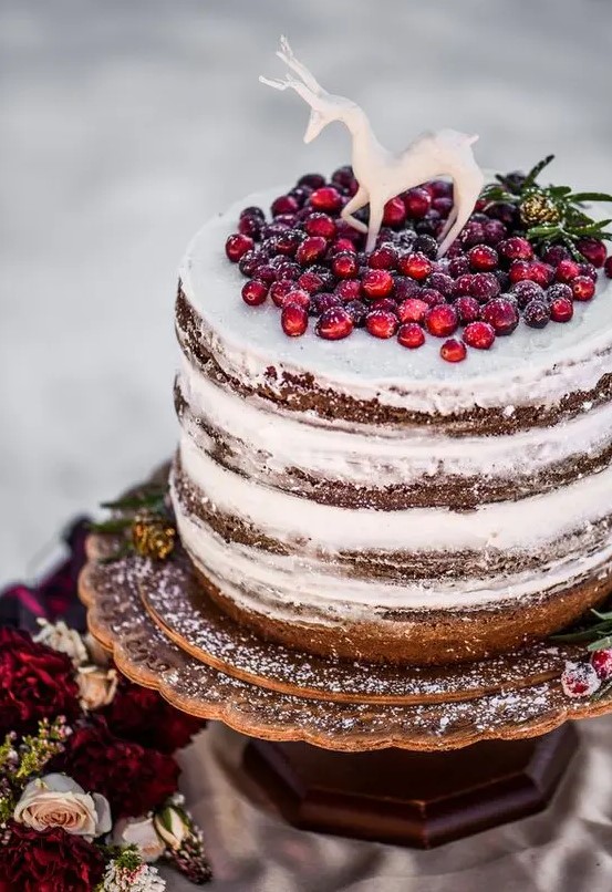 a naked wedding cake topped with cranberries and a sugar deer is a lovely idea for a woodland winter wedding