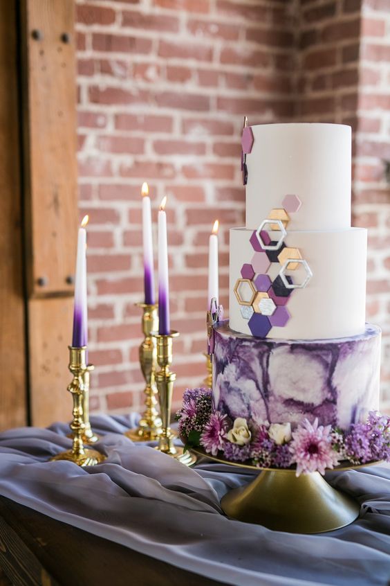 a pretty and bold wedding cake with white and purple watercolor tiers, with sugar hexagons in white, gold, purple and black is very chic