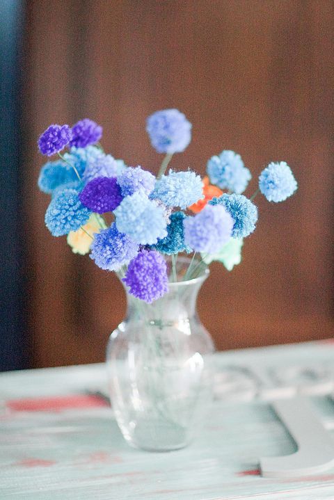 a simple wedding decoration - a glass vase with colorful yarn pompoms on sticks is a great example of a wedding centerpiece