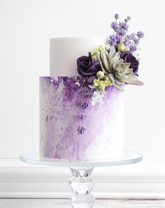 a pretty and delicate wedding cake with a white and watercolor purple tier, with dark purple and lilac blooms and a succulent is wow