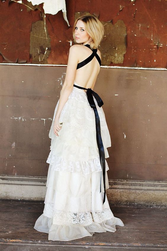 a romantic A-line white lace wedding dress with lace and ruffle tiers plus a train, a black silk ribbon that creates a criss cross back and a bow