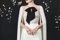 20 an elegant neutral wedding dress with a lace bodice, a plain skirt, a capelet, a black bow on the front for a refine dlook