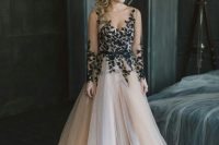 21 a beautiful nude A-line wedding dress with a bodice and sleeves accented with black floral applique and a tulle layered skirt with a train