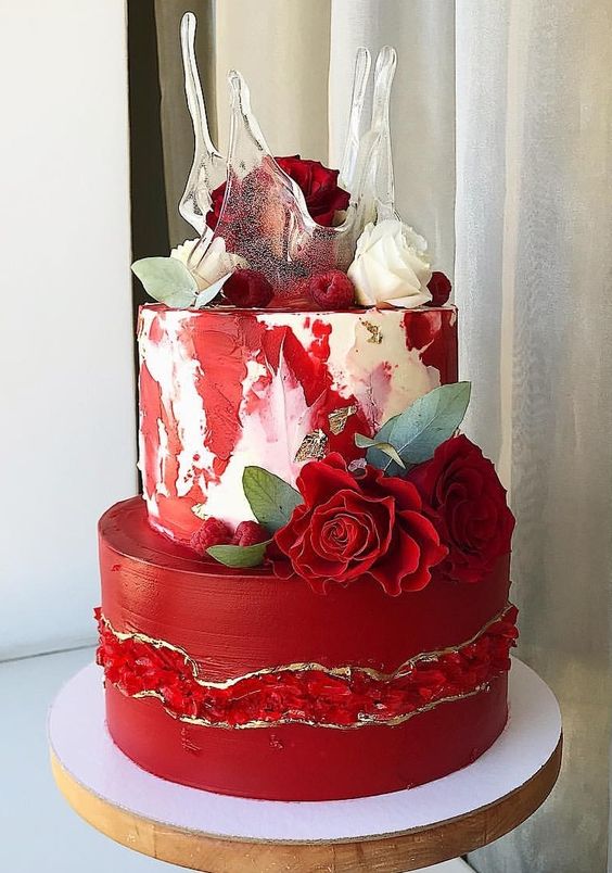 a chic red wedding cake with geode touches, red and white watercolors, red roses, raspberries and sugar splashes on top is a work of art