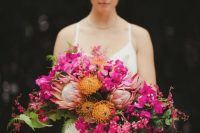 22 a dimensional and textural cascading wedding bouquet of hot pink blooms, pincushion proteas, king proteas, greenery and leaves for a bold wedding