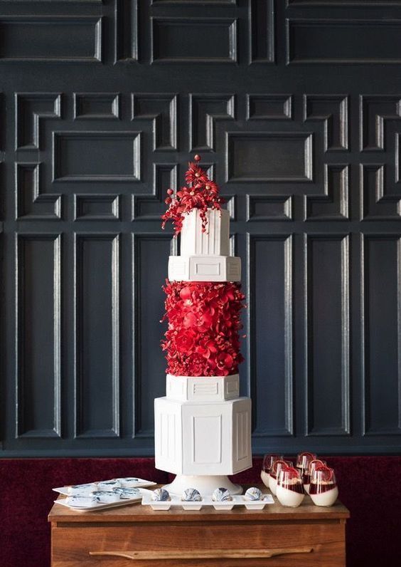 a jaw-dropping wedding cake with white geometric tiers, with a red flower tier and some red flowers on top is a fantastic idea for a refined wedding