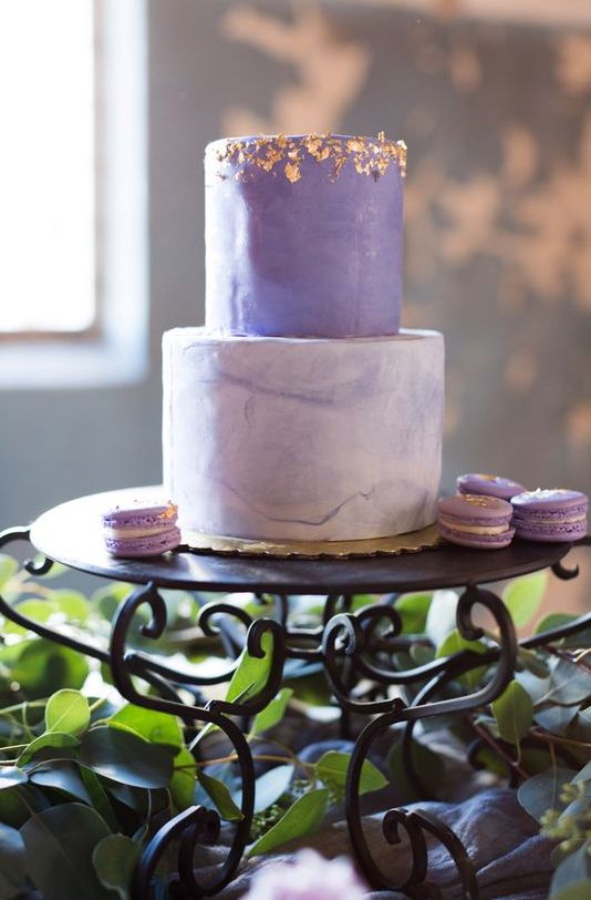 a refined modern wedding cake with a violet and a purple marble tier, with gold foil and matching macarons around is wow